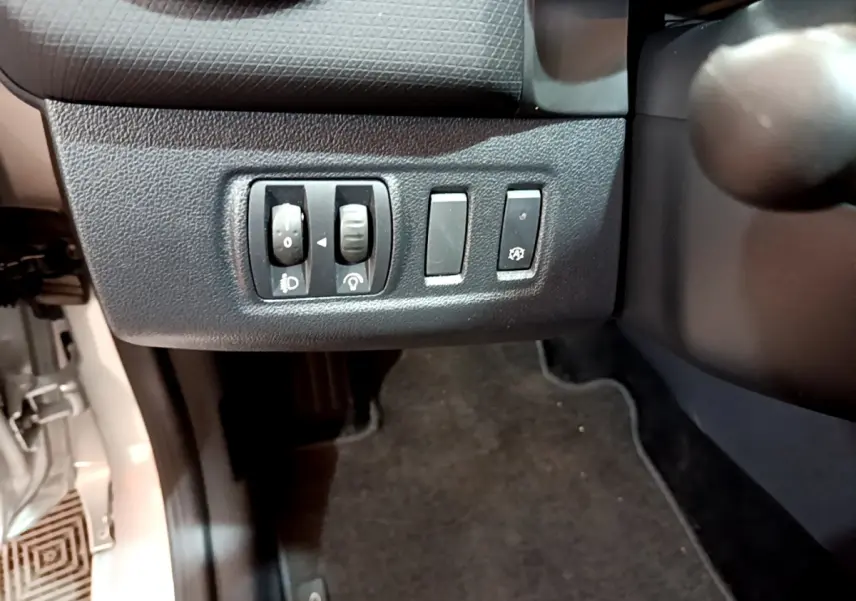 Gros plan sur les commandes de réglage des phares et autres boutons à gauche du volant dans une Renault Clio Business gris clair 2019.