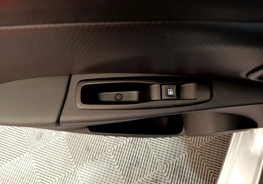 Gros plan sur la commande de lève-vitre côté conducteur de la Renault Clio Business gris clair, intérieur noir.