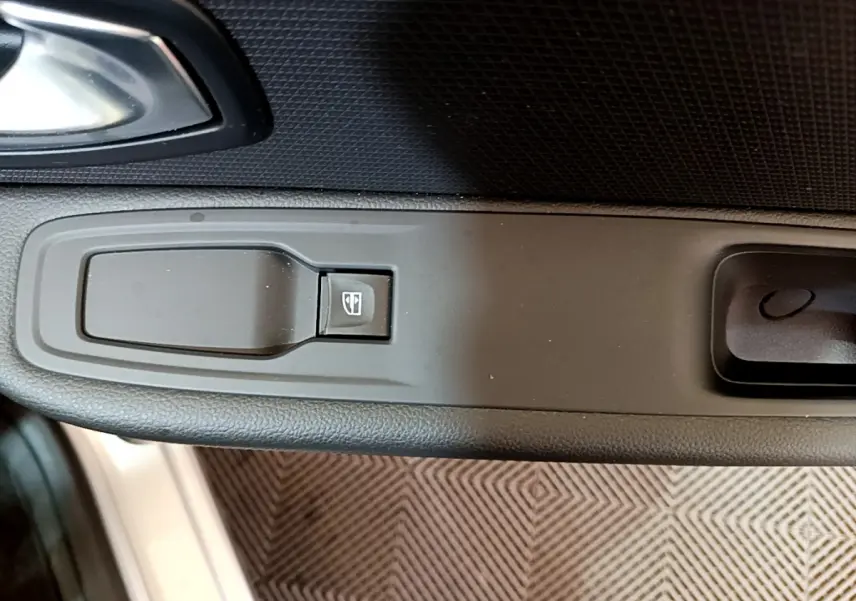 Gros plan sur le bouton de lève-vitre côté conducteur dans l'intérieur noir de la Renault Clio Business gris clair 2019.