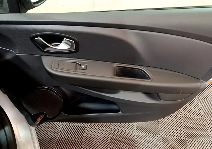 Vue rapprochée de la porte avant gauche de la Renault Clio Business gris clair, avec poignée et commande de vitre noire.