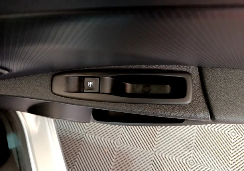 Gros plan sur la commande de lève-vitre côté gauche de la porte d’une Renault Clio Business gris clair de 2019.