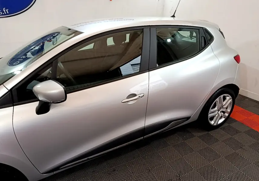 Profil côté gauche d'une Renault Clio Business TCe 90 gris clair, avec jantes alliage et poignées de porte assorties.