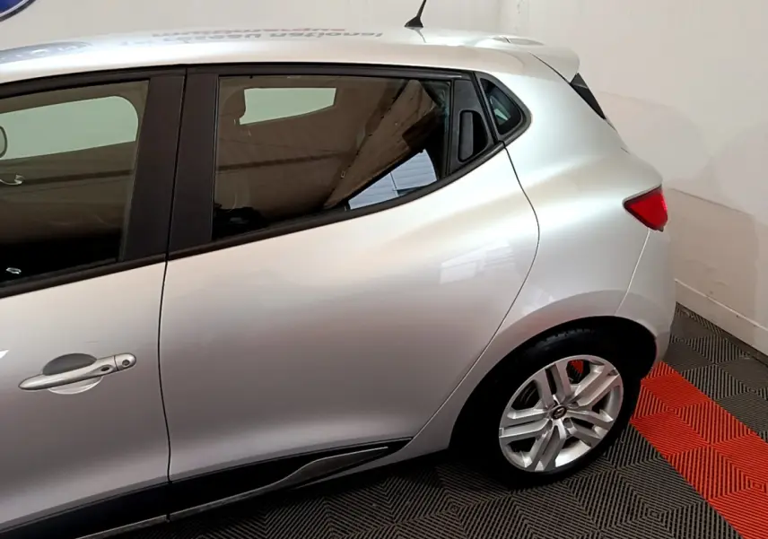 Vue latérale côté gauche d'une Renault Clio Business TCe 90 gris clair, mettant en valeur la porte arrière et la jante alliage.