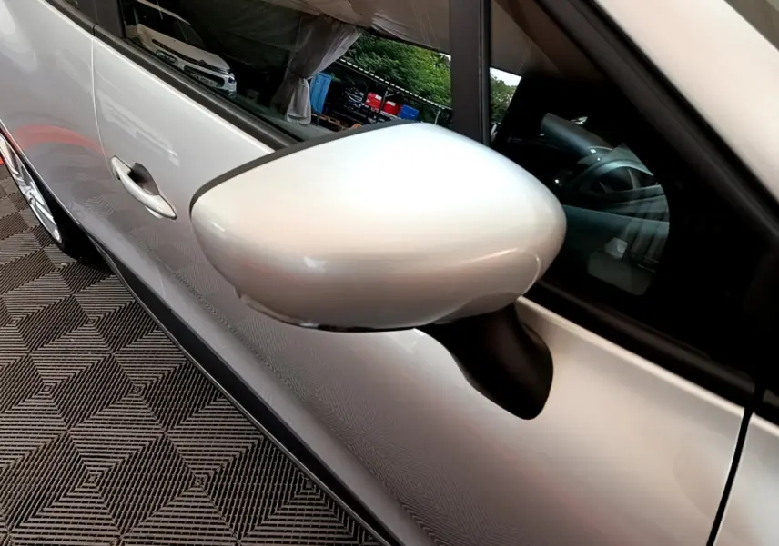 Gros plan sur le rétroviseur côté gauche d'une Renault Clio Business TCe 90 gris clair, avec reflet du véhicule.