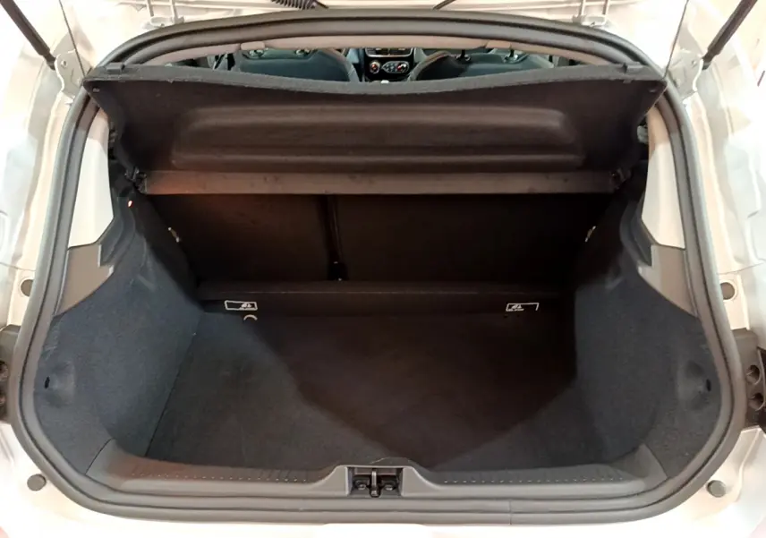 Vue plongeante sur le coffre ouvert d'une Renault Clio Business TCe 90 gris clair, intérieur spacieux et propre.