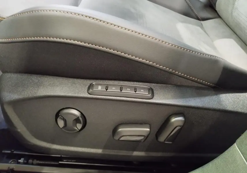 Détail des commandes de réglage électrique du siège conducteur en suédine noire avec surpiqûres cuivrées dans une CUPRA Formentor noir métal.
