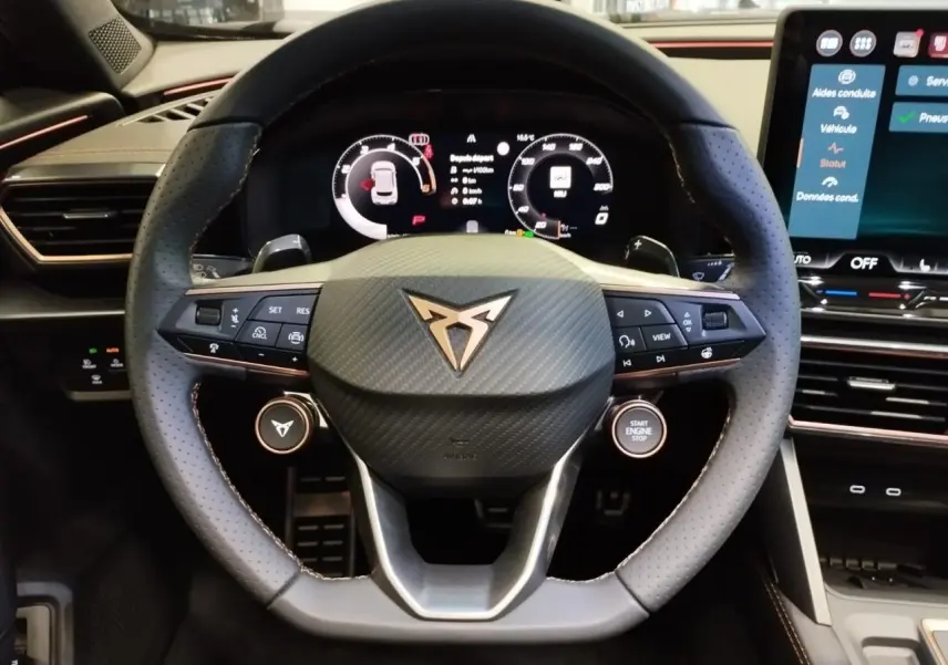 Volant Cupra en cuir perforé noir avec logo cuivré, vue frontale du poste de conduite digital et écran tactile HD.