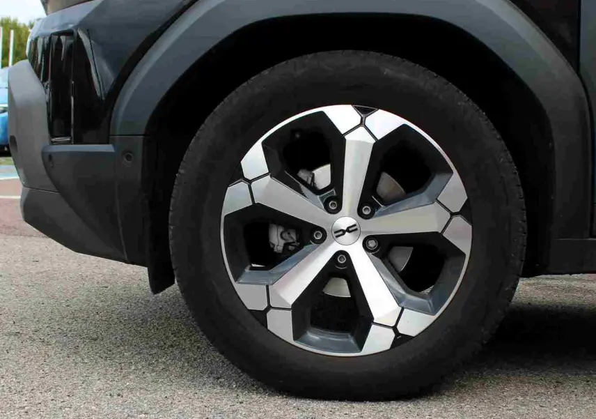 Gros plan sur la roue avant gauche du Dacia Duster noir 2025 avec jante alliage 18 pouces diamantée Tagasan.