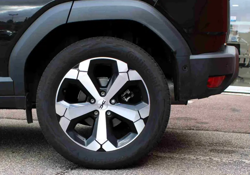 Gros plan sur la roue arrière droite du Dacia Duster noir 2025 avec jante alliage diamantée Tagasan.