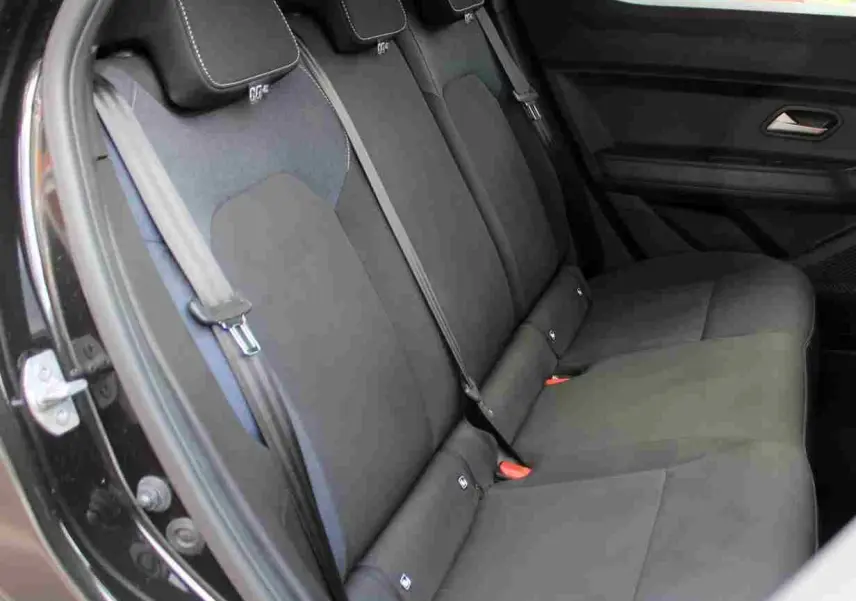 Vue latérale intérieure montrant la banquette arrière noire avec appuie-têtes et ceintures dans un Dacia Duster 2025.