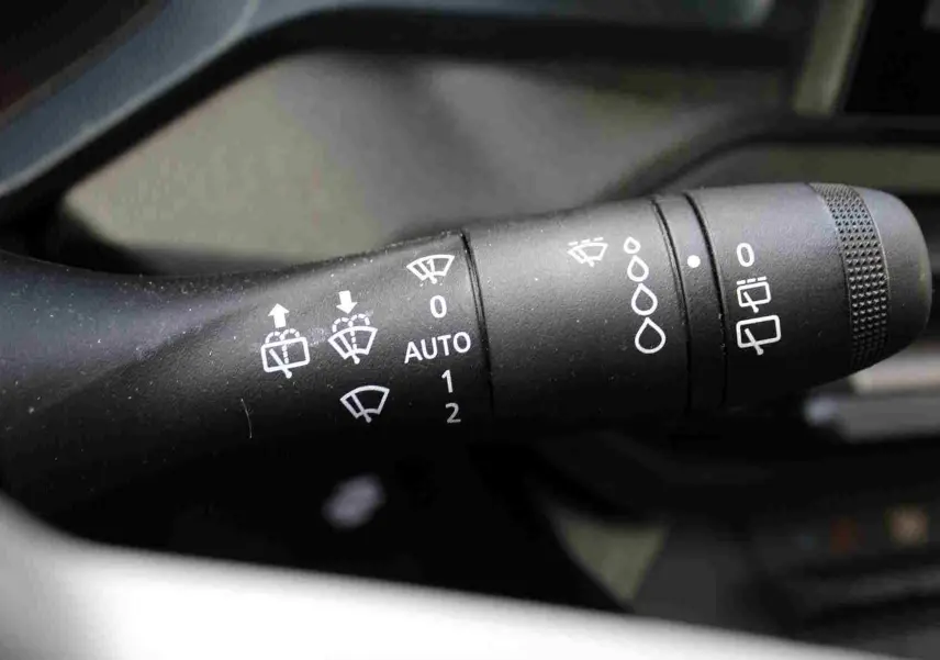 Gros plan sur la commande des essuie-glaces du Dacia Duster 2025, avec symboles blancs sur fond noir.