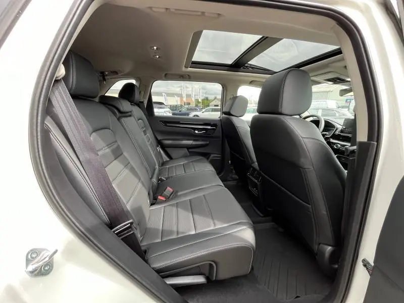 Vue intérieure côté gauche du Honda CR-V 2024 blanc nacré, montrant les sièges arrière en cuir noir et toit panoramique.