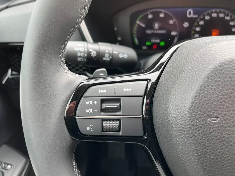 Gros plan sur les commandes audio et volume au volant cuir noir du Honda CR-V 2024 hybride.