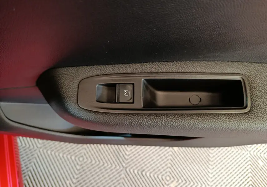 Gros plan sur la commande de lève-vitre côté conducteur de la Renault Clio Techno TCe 90 rouge 2024.