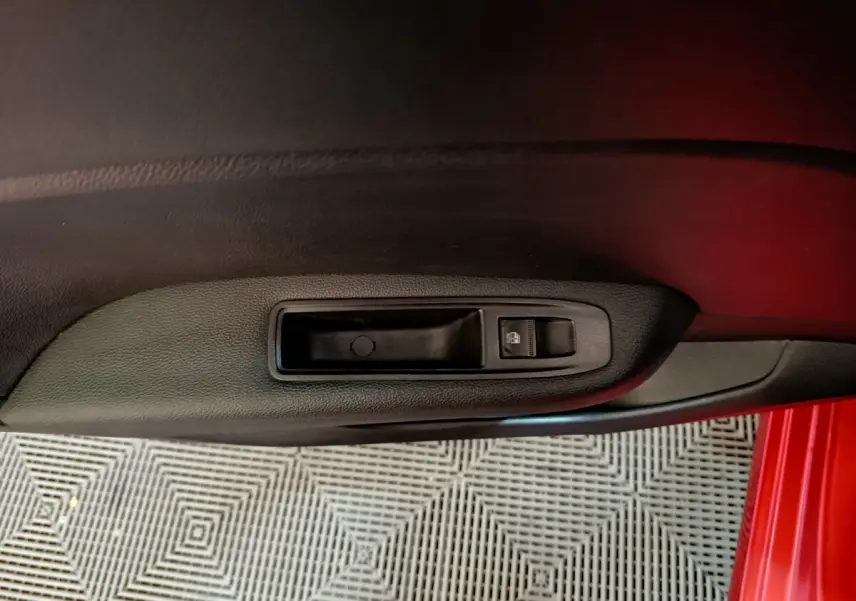 Gros plan sur la commande de lève-vitre côté conducteur de la Renault Clio Techno TCe 90 rouge 2024.