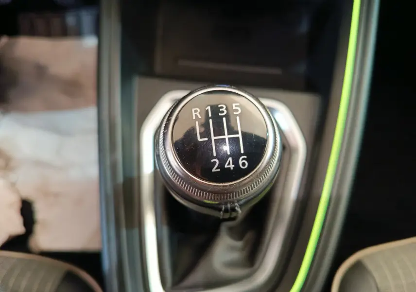 Gros plan sur le levier de vitesses manuel de la Renault Clio Techno TCe 90, entouré d'un éclairage d'ambiance vert pâle.