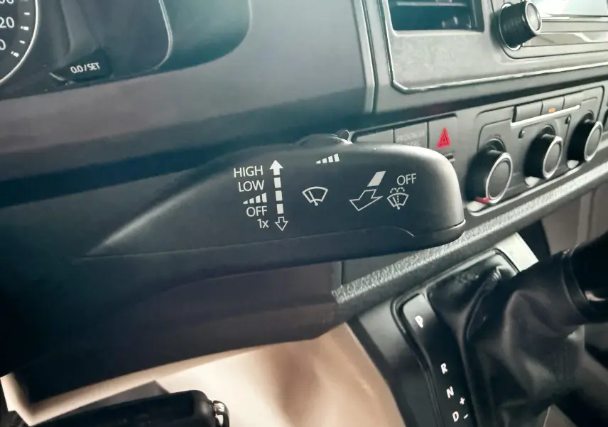Gros plan sur la commande d’essuie-glace et la console centrale du Volkswagen Transporter blanc, vue intérieure côté conducteur.