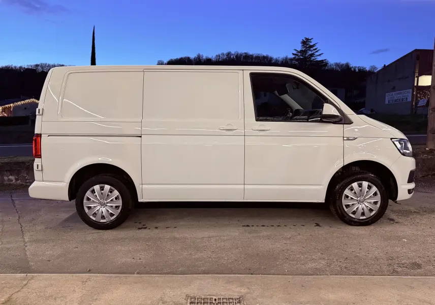 Vue de profil côté droit d’un Volkswagen Transporter L1H1 blanc de 2018, fourgon utilitaire avec jantes acier et enjoliveurs.