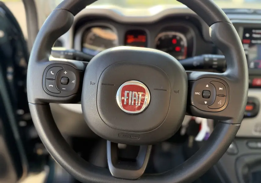 Gros plan sur le volant noir de la Fiat Panda City Cross 2023 avec commandes intégrées et logo rouge central.