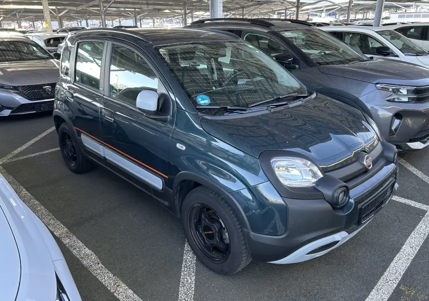 Vue de profil côté gauche d'une FIAT Panda City Cross gris minuit avec détails orange et coques de rétroviseurs blanches.
