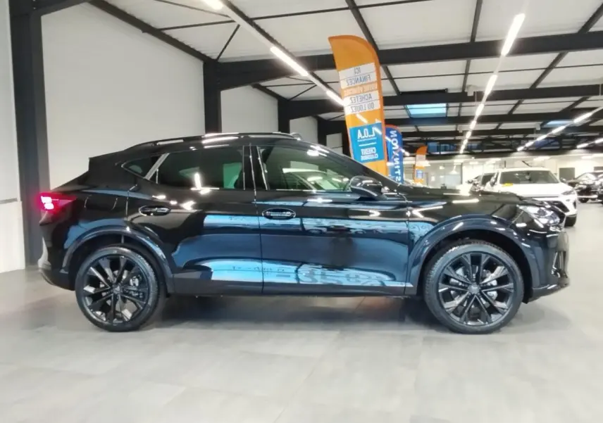 Vue de profil côté gauche d'une CUPRA Formentor noire métal avec jantes alliage noires dans un showroom.