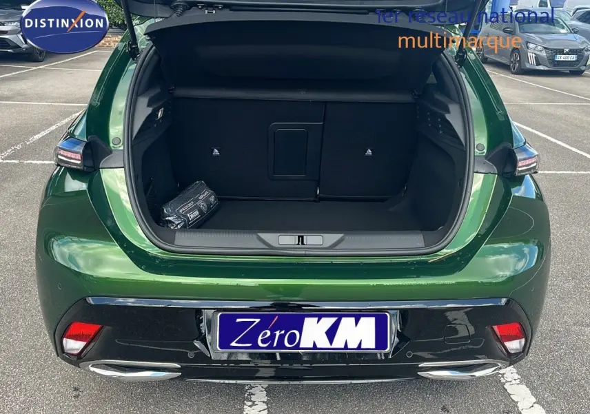 Vue arrière d'une Peugeot 308 1.2 Hybrid 136ch Allure en vert olivine métal avec coffre ouvert sur parking.