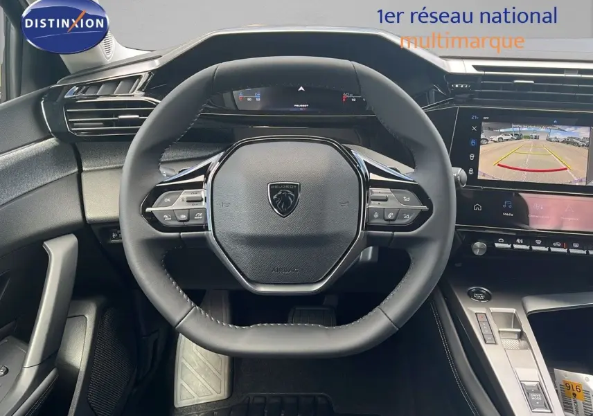 Vue intérieure centrée sur le volant Peugeot 308 2024, avec tableau de bord numérique et écran de caméra de recul.