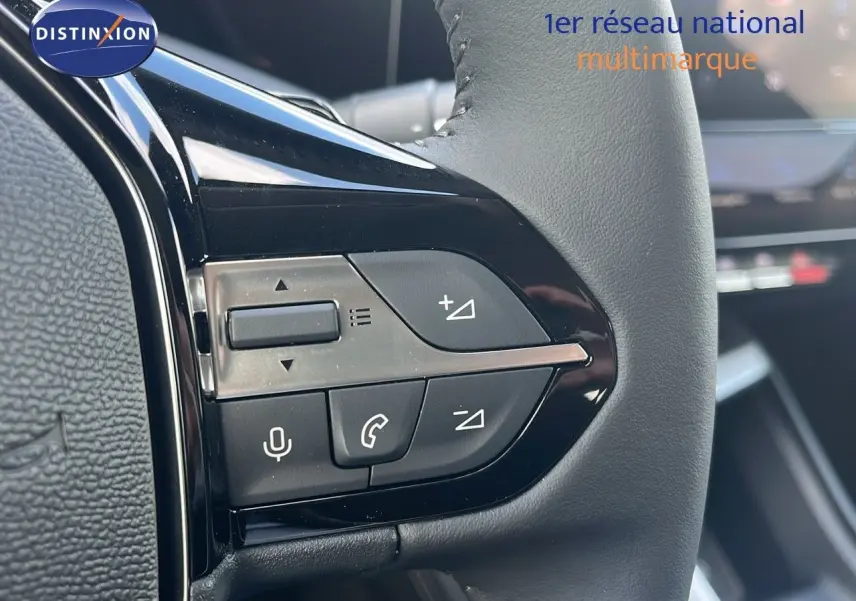 Gros plan sur les commandes au volant en cuir noir de la Peugeot 308 hybride 2024, avec boutons de volume et appel.