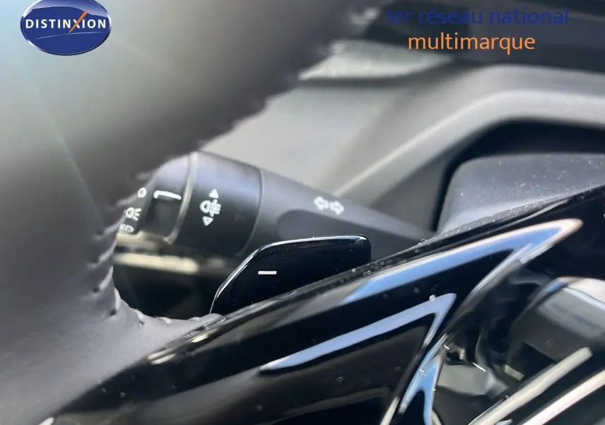 Gros plan sur la palette de changement de vitesse au volant d'une Peugeot 308 hybride, intérieur noir.