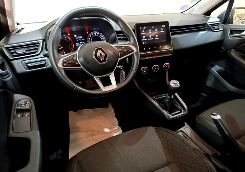 Vue intérieure avant de la Renault Clio Business TCe 90 2022, volant cuir, écran tactile central et levier de vitesse manuel visibles.