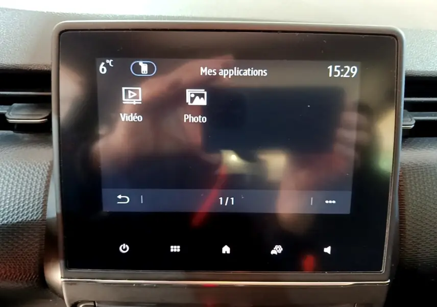 Écran tactile central de la Renault Clio Business gris foncé, affichant le menu applications vidéo et photo.