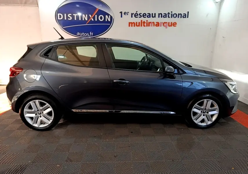 Profil droit d'une Renault Clio Business TCe 90 gris foncé, stationnée en intérieur sur sol damier noir et rouge.