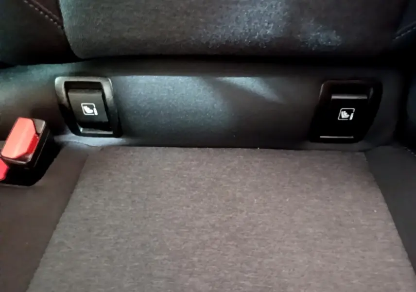 Gros plan sur les commandes de rabattement des sièges arrière et la ceinture de sécurité dans une Renault Clio Business gris foncé.