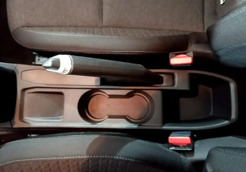 Vue plongeante sur la console centrale noire avec frein à main manuel et sièges tissu gris foncé d'une Renault Clio Business 2022.