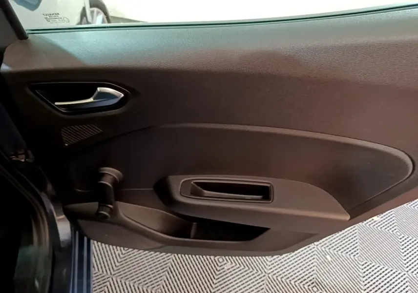 Vue intérieure du panneau de porte côté gauche d'une Renault Clio Business TCe 90 gris foncé, avec poignée et manivelle de vitre.