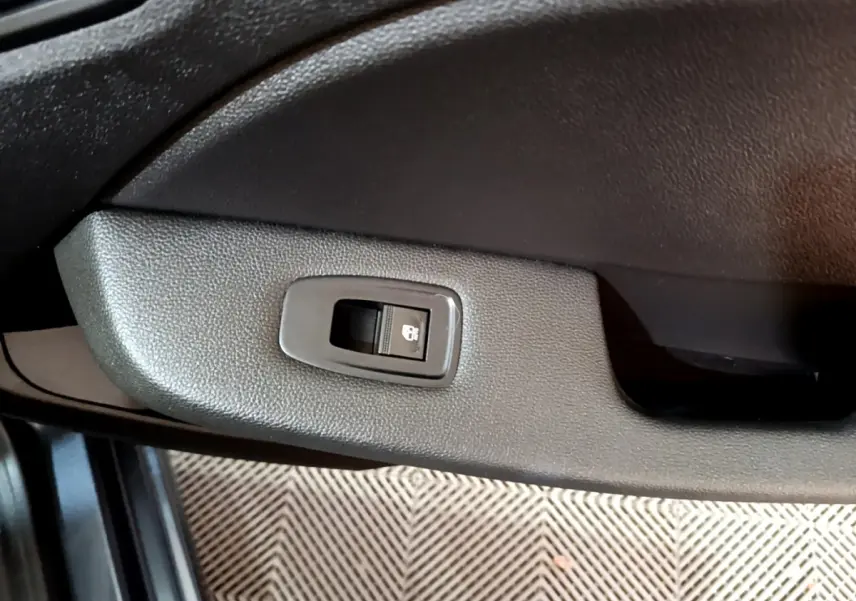 Bouton de commande de vitre électrique sur la portière côté gauche d'une Renault Clio gris foncé 2022.