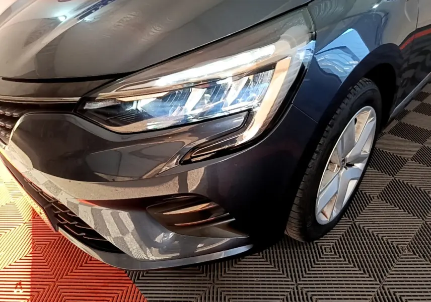 Gros plan sur l'avant droit de la Renault Clio Business TCe 90 gris foncé, mettant en valeur le phare LED et la jante alliage.