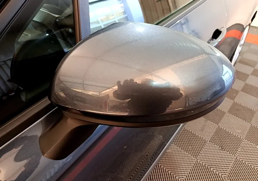 Rétroviseur côté gauche gris foncé de la Renault Clio Business TCe 90 vue en gros plan avec reflet intérieur.