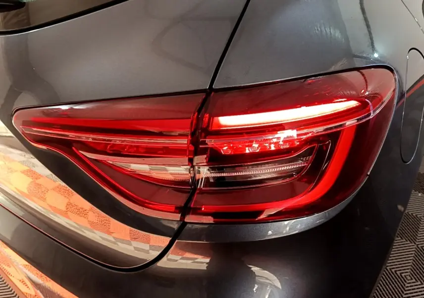 Gros plan sur le feu arrière droit rouge d'une Renault Clio Business gris foncé 2022, avec la trappe à carburant visible.