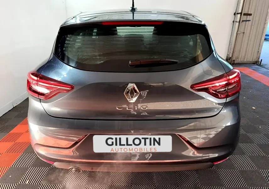 Vue arrière d'une Renault Clio gris foncé avec feux LED et logo centré sur un sol à damier noir et orange.