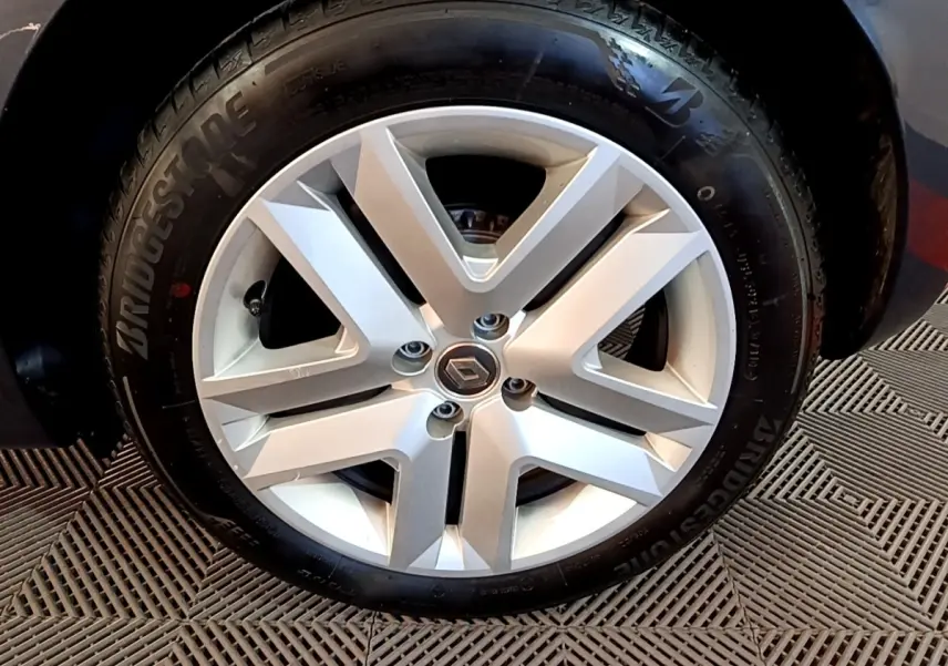 Gros plan sur la jante alliage argentée avec logo Renault au centre, roue avant d'une Clio Business gris foncé.