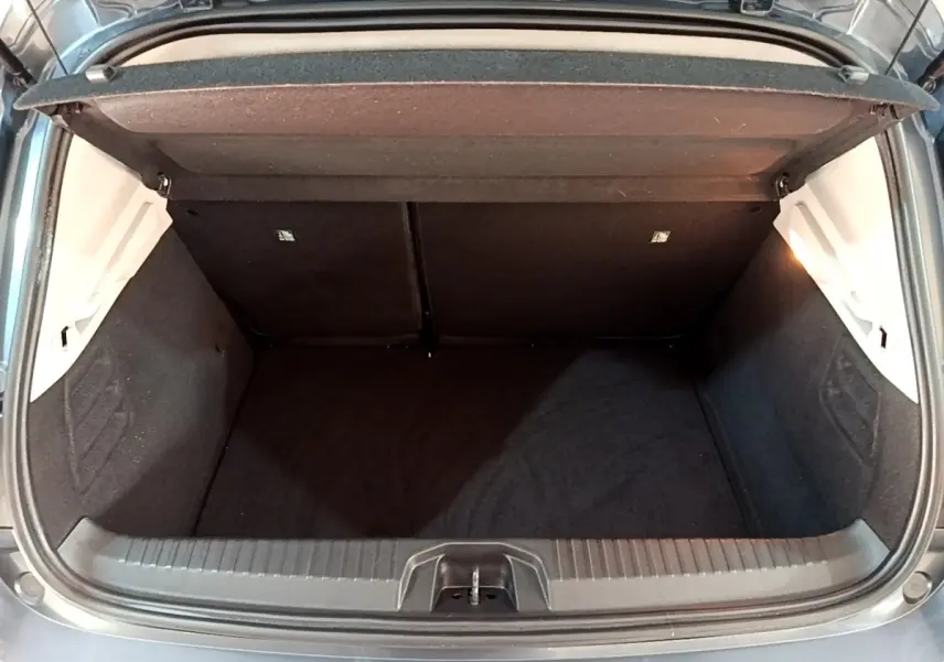 Coffre ouvert vu de l'arrière d'une Renault Clio Business TCe 90 gris foncé, montrant l'espace de chargement vide.