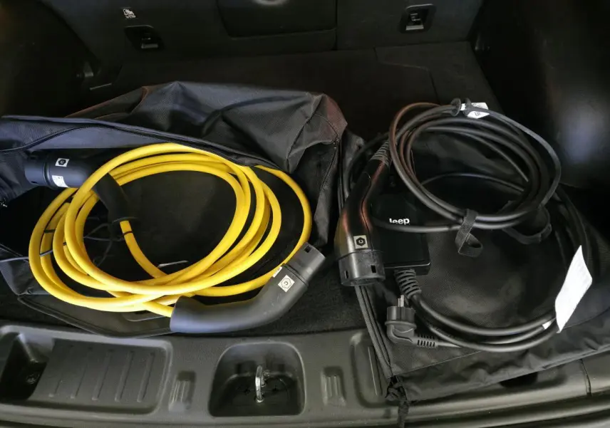 Vue rapprochée du coffre du Jeep Compass Trailhawk 2024 montrant deux câbles de recharge, jaune et noir.