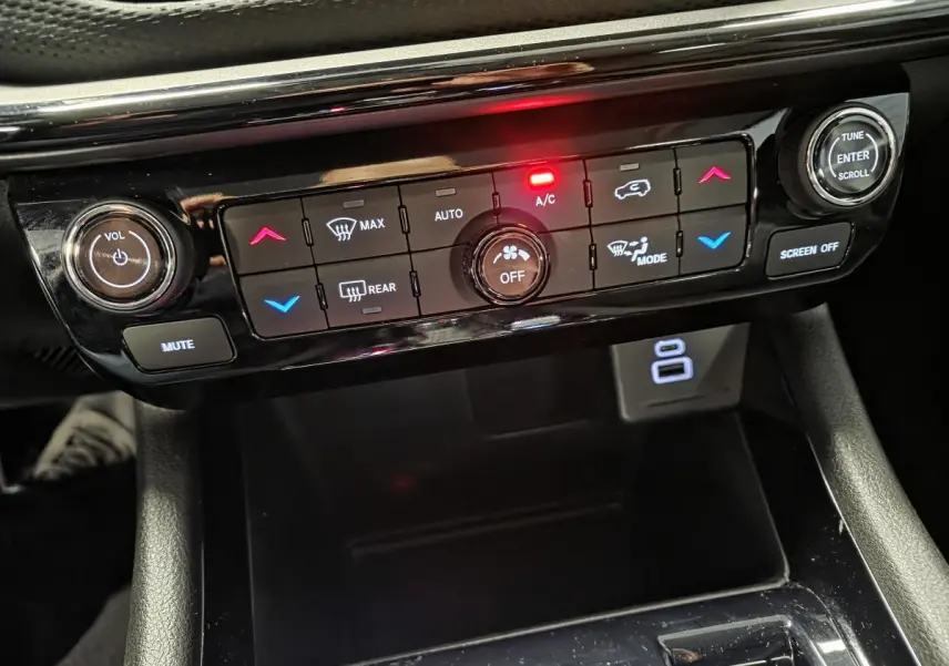 Tableau de bord noir du Jeep Compass 2024 avec commandes climatisation et réglages audio éclairés en rouge et bleu