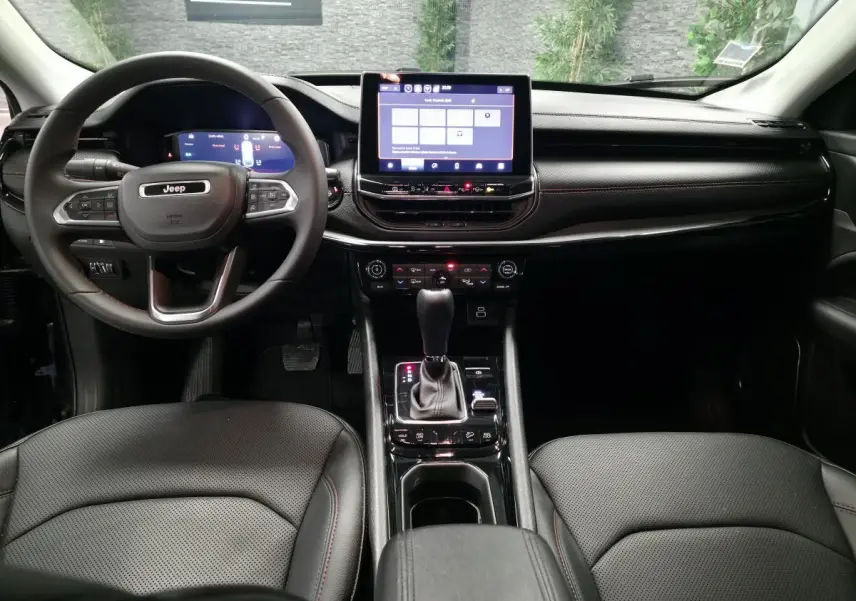 Intérieur noir du Jeep Compass 2024 vu de face, avec tableau de bord numérique et écran tactile central.