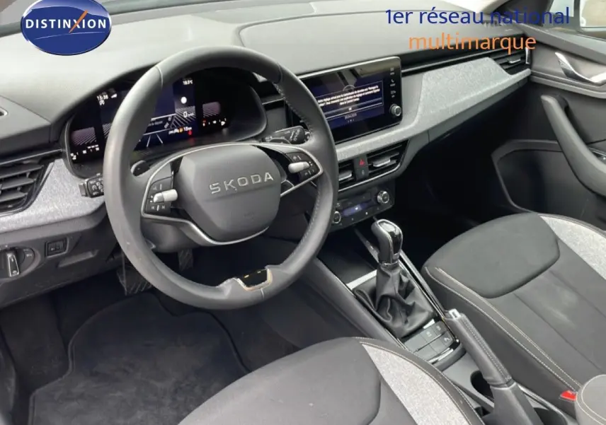 Vue intérieure côté conducteur du Skoda Kamiq 2025 avec volant multifonction, tableau de bord numérique et sellerie tissu noir et gris.