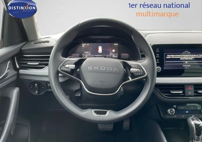 Vue intérieure centrée sur le volant SKODA d’un KAMIQ 2025, tableau de bord numérique et écran tactile visibles.