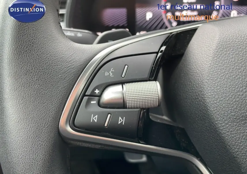 Gros plan sur les commandes au volant côté gauche du Skoda Kamiq blanc glacier, mettant en valeur la molette et les boutons multifonctions.