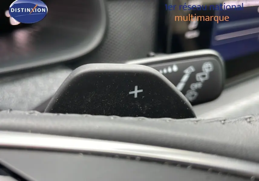 Gros plan sur la palette de changement de vitesse "+" du volant d'un Skoda Kamiq blanc glacier, intérieur noir.