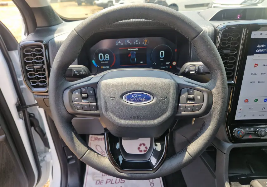 Vue centrée sur le volant du Ford Ranger Super Cabine blanc, avec tableau de bord numérique et écran tactile visible.